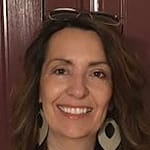 woman smiles with glasses on her head, wearing large, round earrings