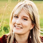Sarah smiles at the camera, with wild grasses blowing in the background